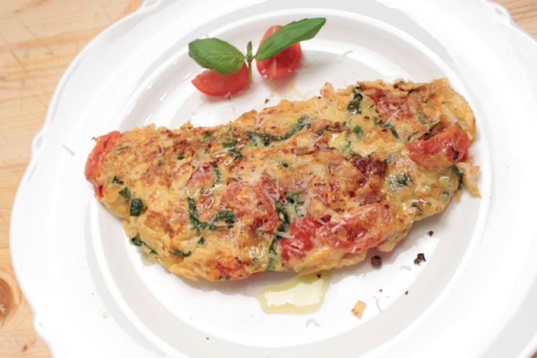 Omelette with tomatoes and basil freshly prepared and nicely decorated. Food picture (c) Thomas Sixt.