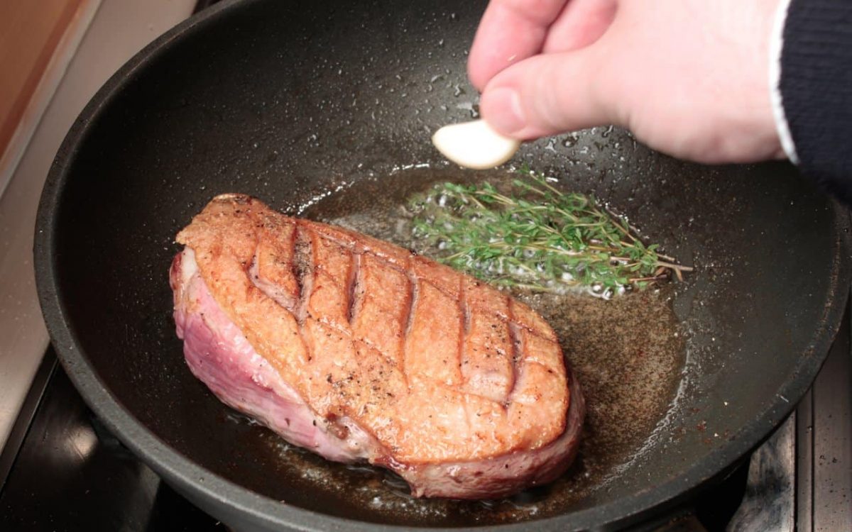 roast duck breast in the pan with herbs and garlic