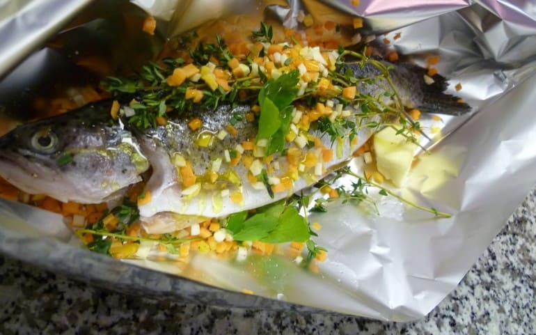 Fish in aluminum foil with vegetables. Herbs and white wine.