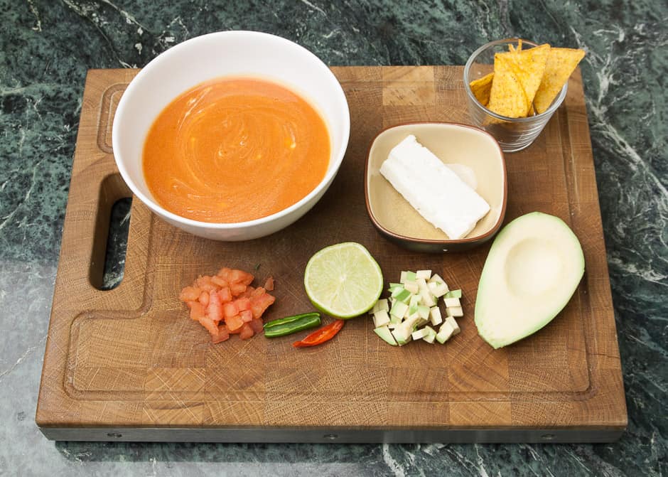 Cold tomato soup with diced tomatoes, chilli, lime, avocado, sheep cheese and corn chips