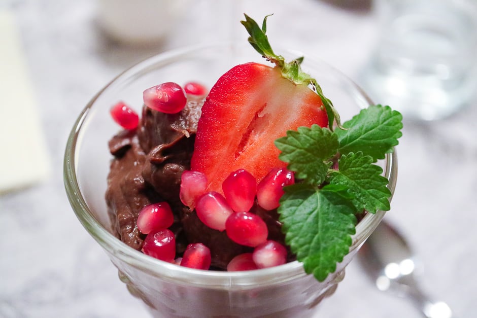 vegan chocolate mousse served as dessert, decorated with strawberries, pomegranate seeds and mint