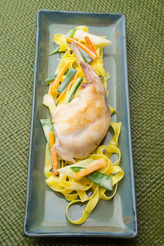 Braised rabbit legs with ribbon noodles and vegetables.