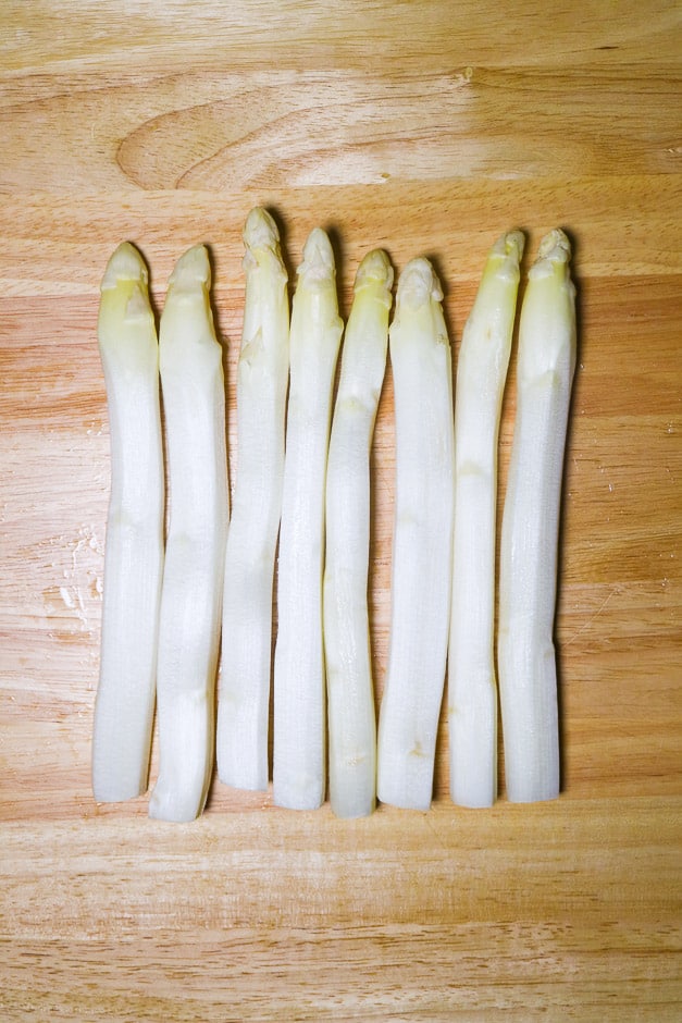 Peeled, white asparagus on a board.