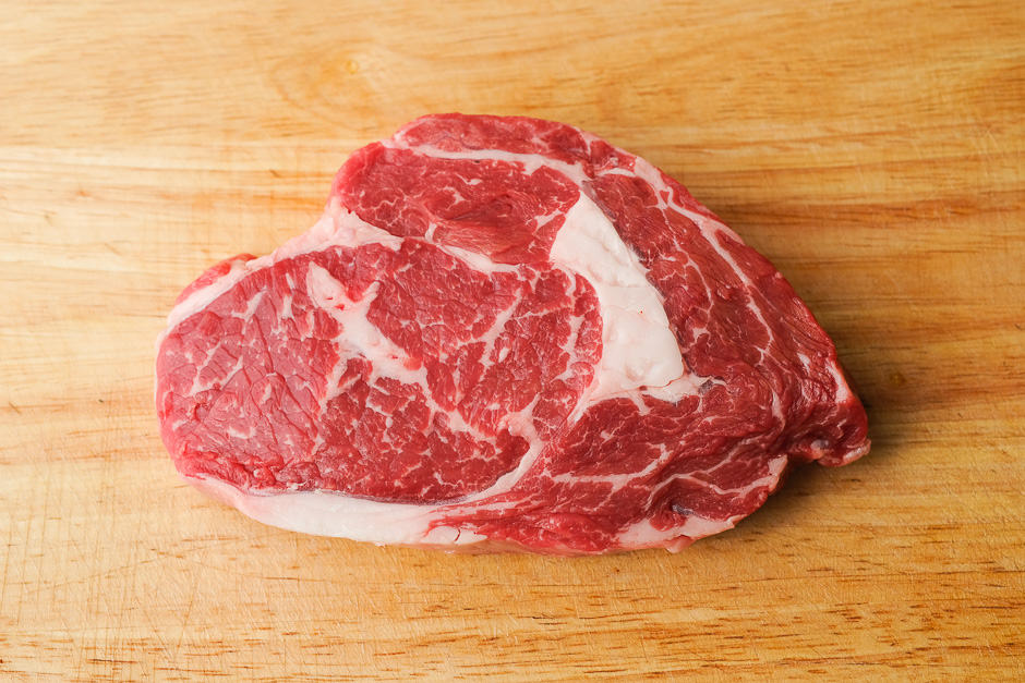 Rib eye steak raw on a kitchen board