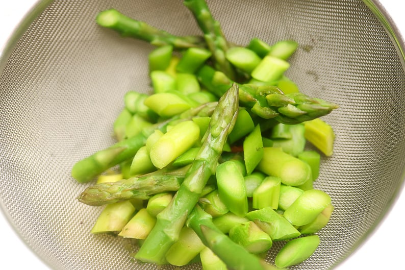 Photographed green asparagus al dente blanched in a colander.