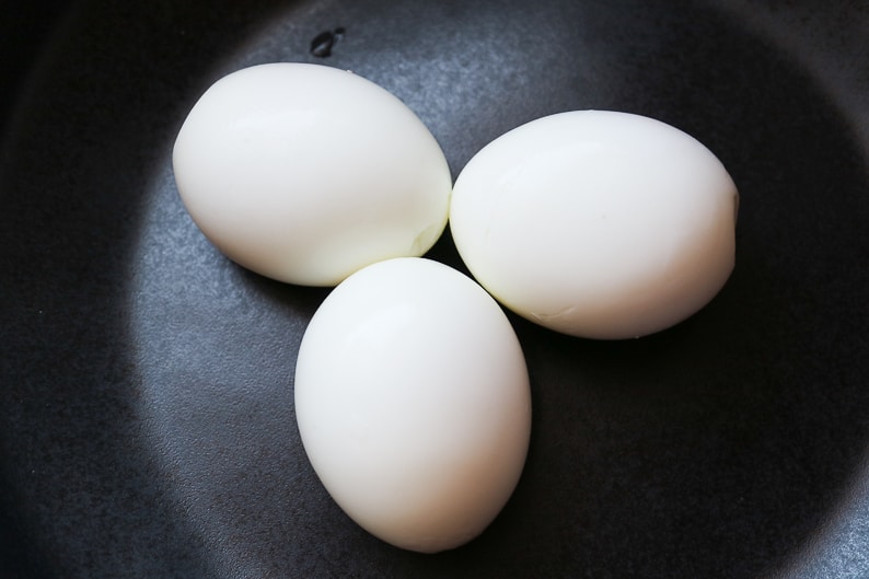 Boiled <br> peeled eggs photographed on a black plate
