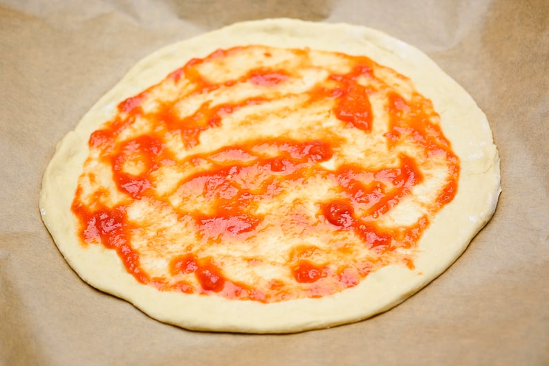 Brush the pizza dough with tomato sauce
