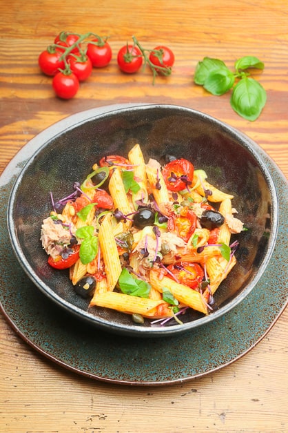 Tuna noodles served with tomatoes and basil.