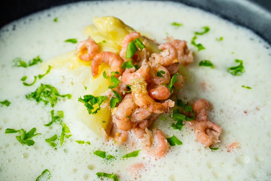Serve asparagus soup with shrimps.