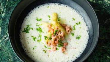Cream of asparagus soup served with asparagus pieces, shrimps and parsley.