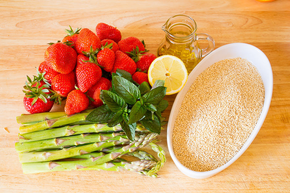 Quinoa salad ingredients asparagus, strawberries on a kitchen board.