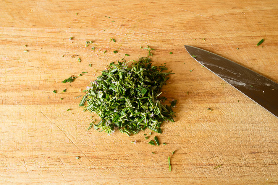 Herbs finely chopped on kitchen board.