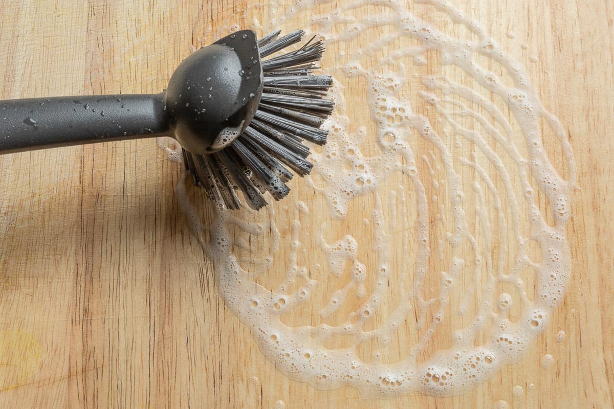 Clean the wooden cutting board with a brush