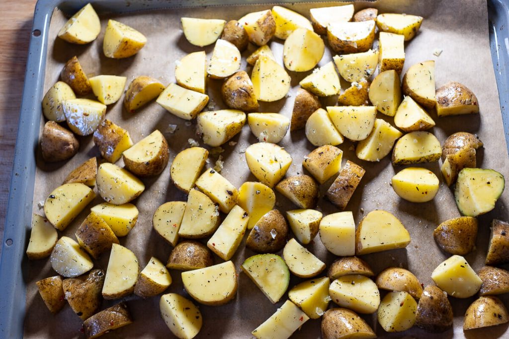 Potato pieces seasoned on the baking sheet