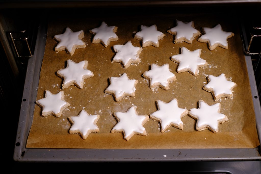 Glazed cinnamon stars on a baking sheet in the oven