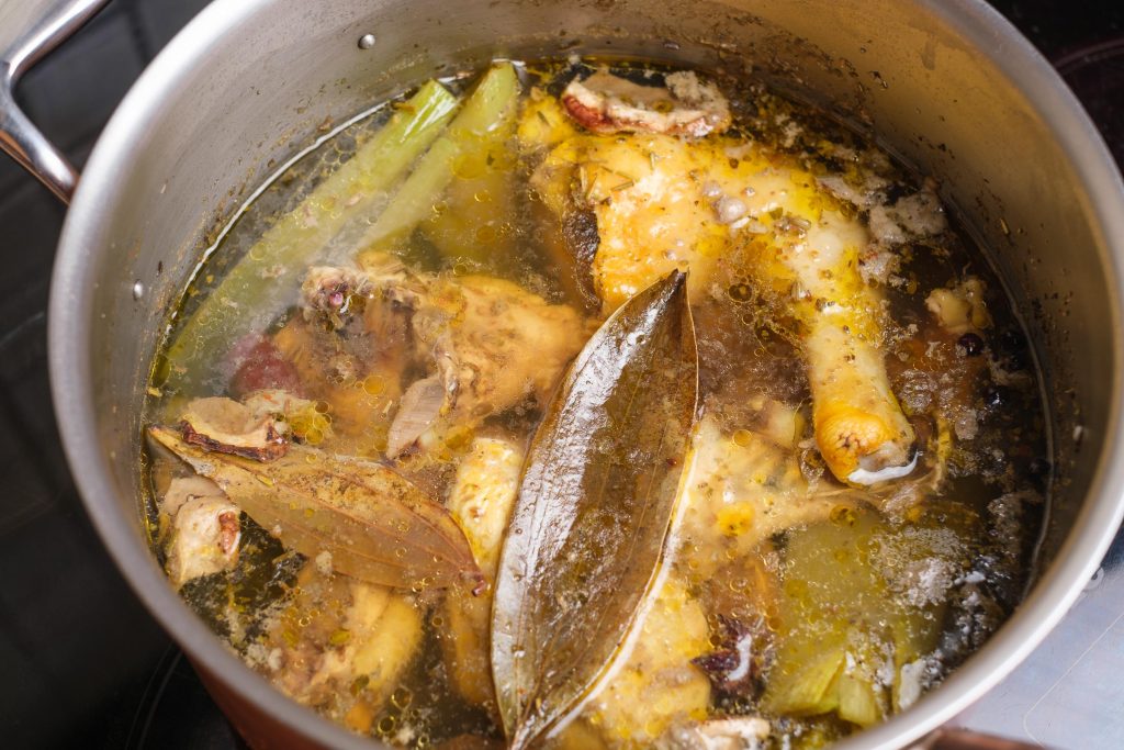 Boiled chicken soup in the pot close-up
