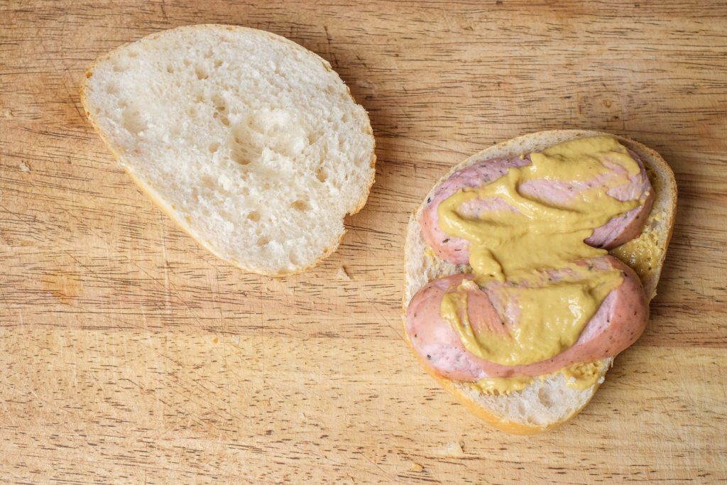 Spread the knacker in the bread roll with mustard