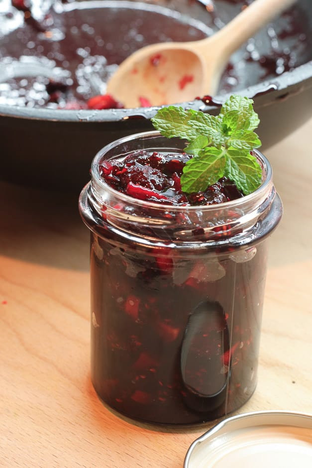 Beerenfrüchte Marmelade in Glas gefüllt mit Minze dekoriert Hochformat