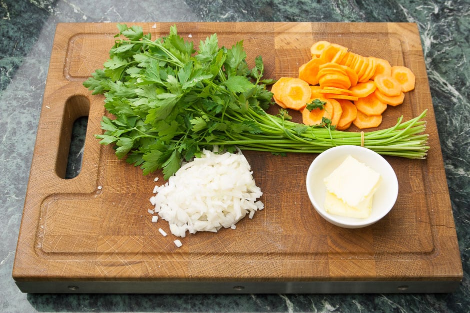 Zutaten für Karottencremesuppe und Karottensuppe auf einem Schneidebrett