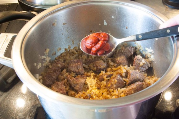 Gulasch-Fleisch und Zwiebelwürfel anbraten und Tomatenmark zugeben.