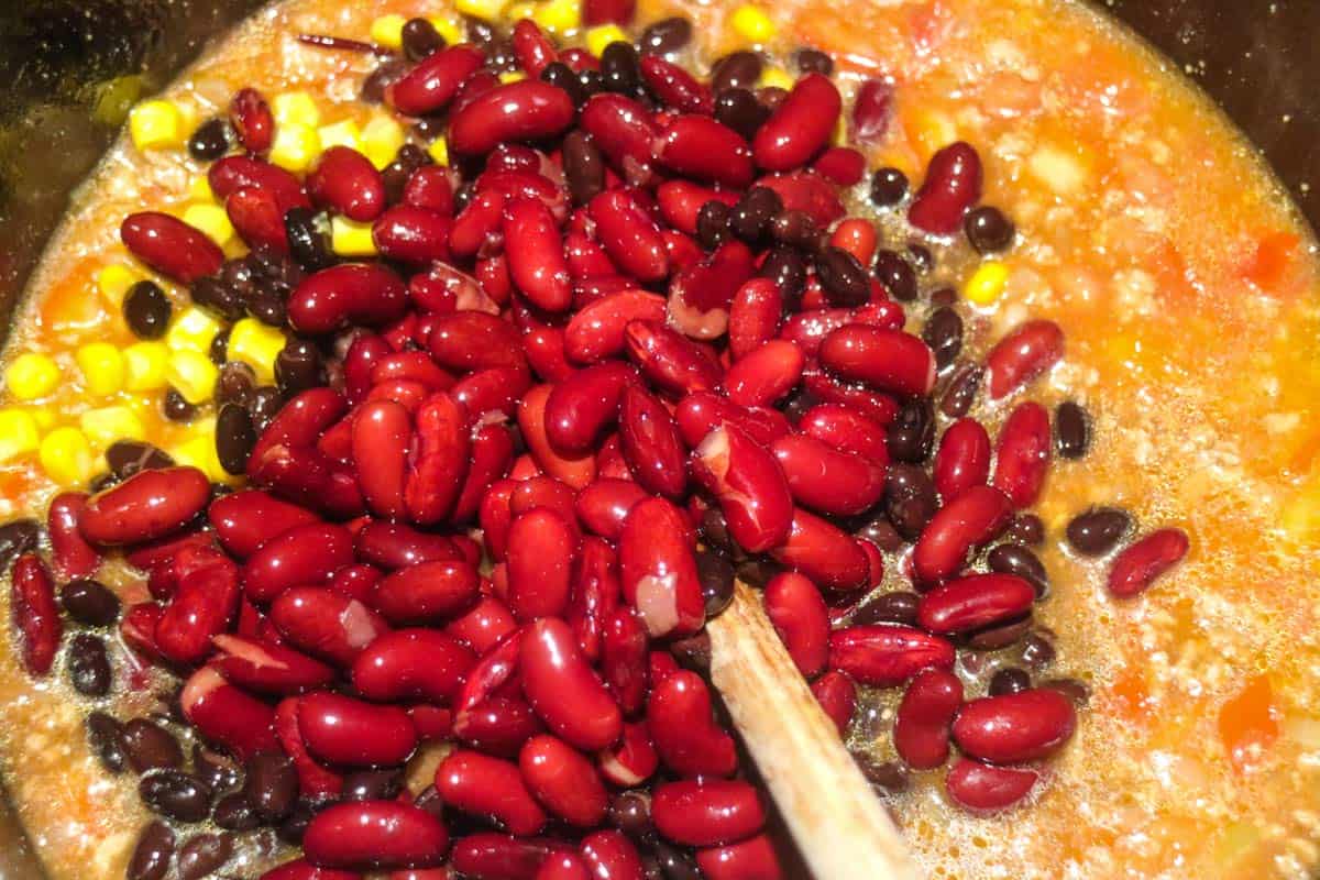 Kidneybohnen und Mais zum Chiliansatz geben