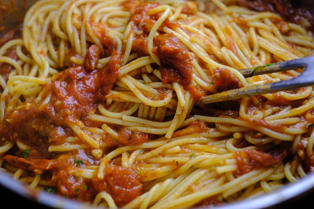 Tomatensoße mit Spaghetti vermischen