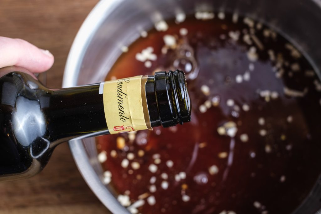 Balsamdressing Essig zu den Gewürzen geben
