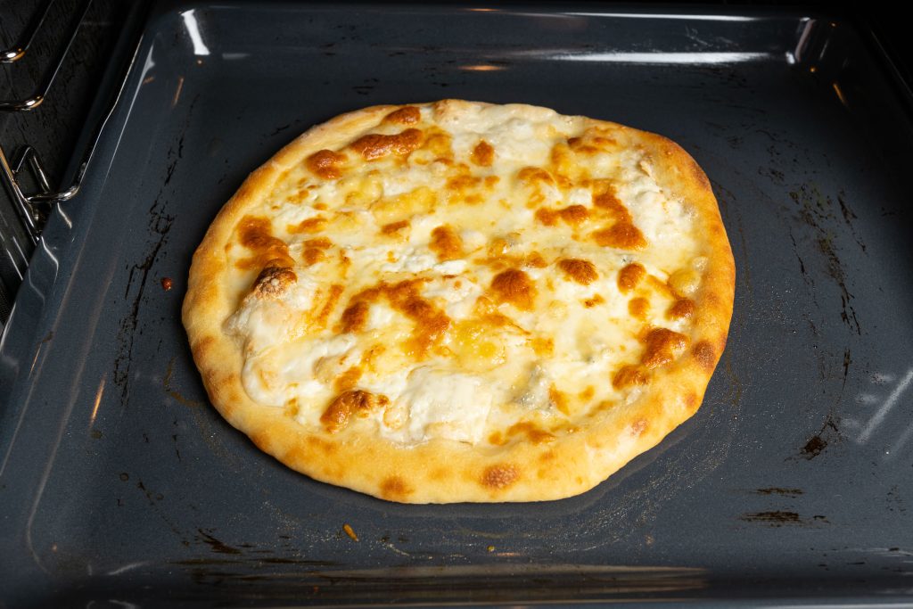 Pizza Quattro Formaggi – Vier-Käse-Pizza – gebacken im Ofen auf dem Backblech.