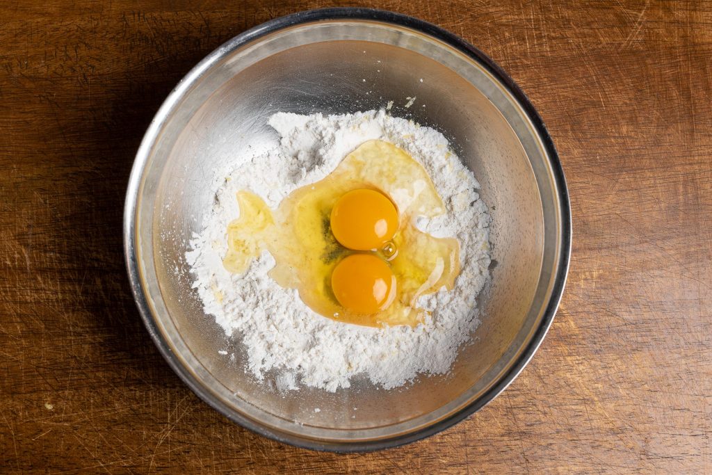 Eier zu Mehl für Pfannkuchenteig geben.