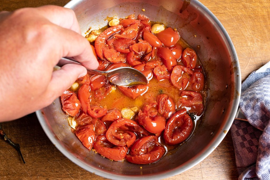 Geschmorte Tomaten im Topf zerkleinern mit Löffel