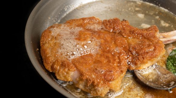 Mailänder Schnitzel in der Pfanne mit Butterschmalz begießen