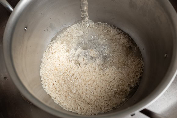 Reis im Topf mit kaltem Wasser waschen