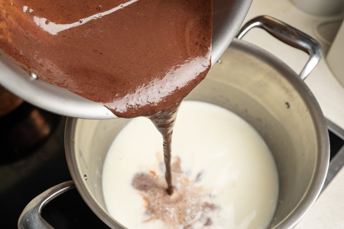 Schokoladensahne zur heißen Milch gießen