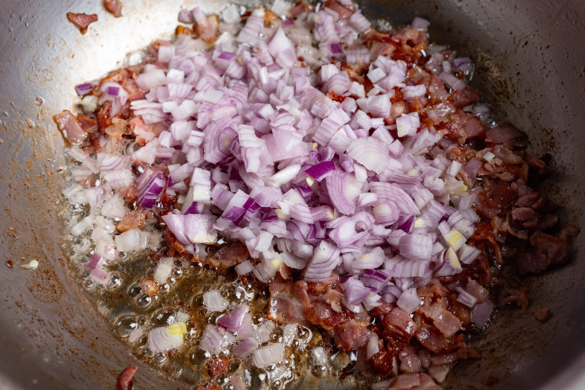 Zwiebelwürfel zum Speck geben