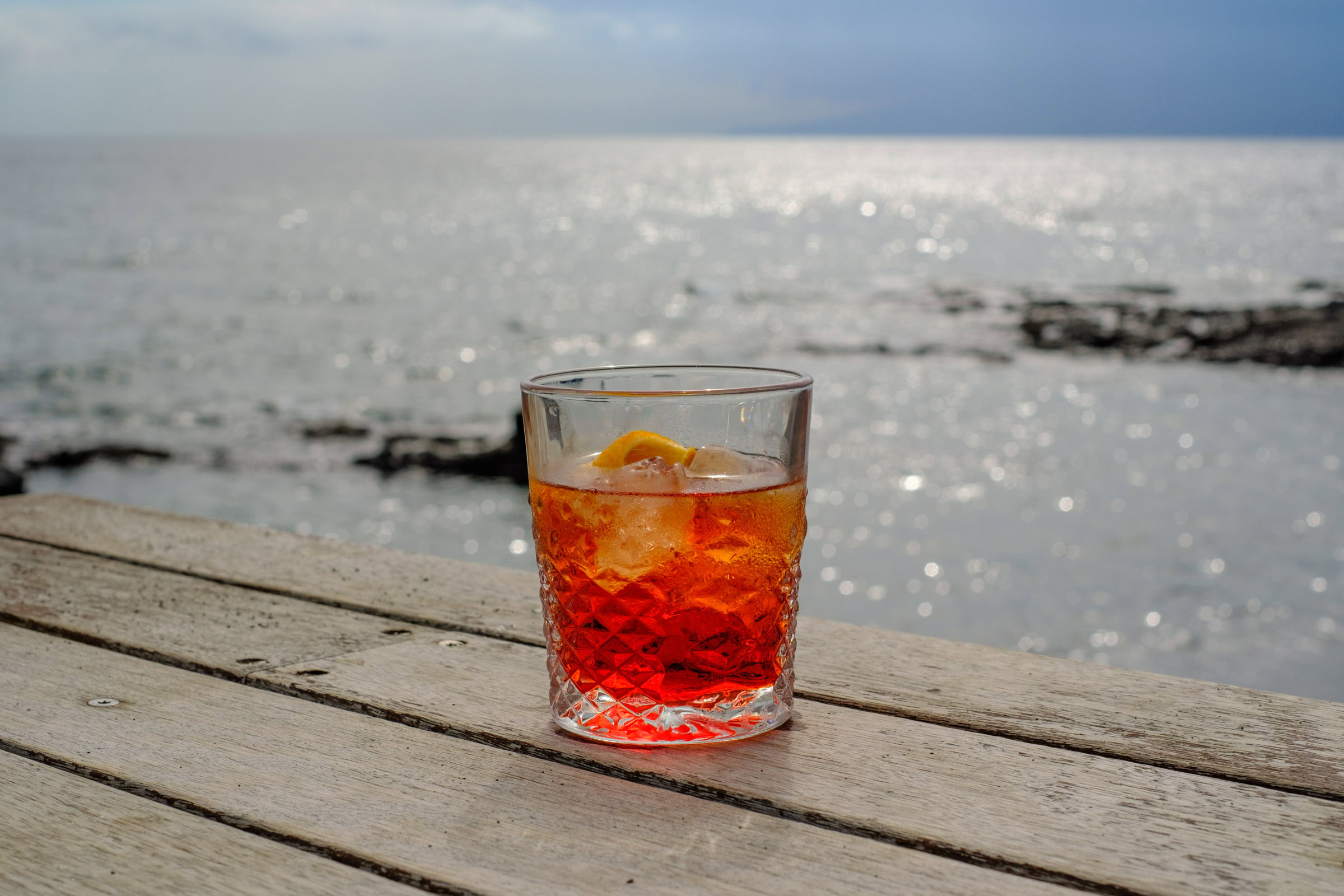 Negroni Cocktail Hintergrund glänzendes Meer