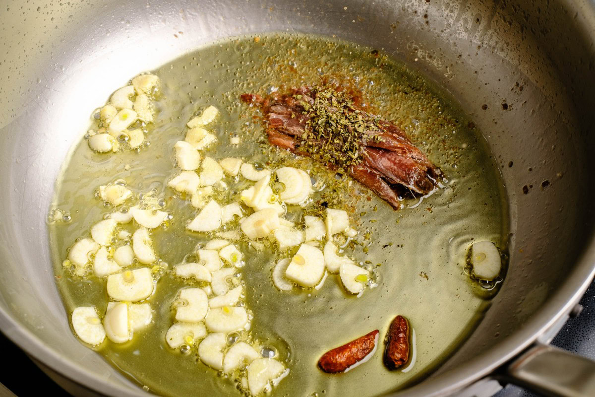 Knoblauch, Chili, Sardellenfilets bzw. Anchovis mit Oregano anschwitzen in Olivenöl