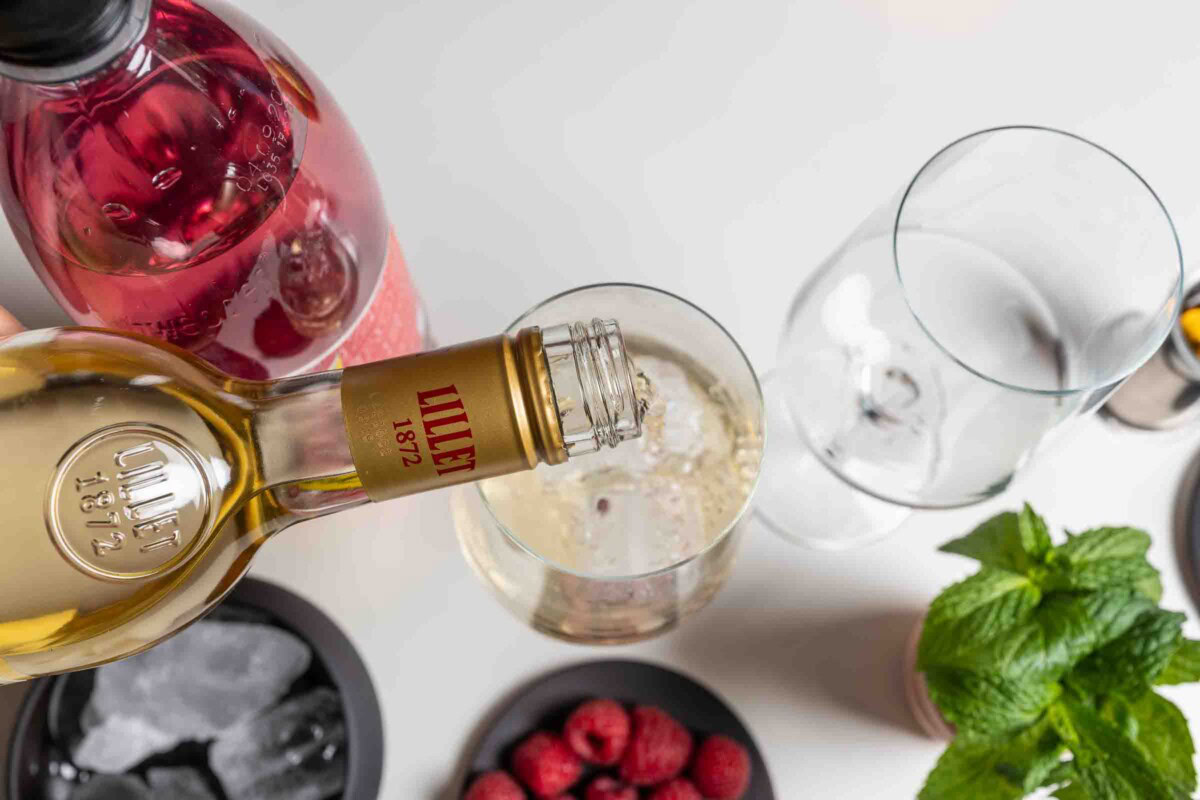 Lillet Blanc wird aus der Flasche in ein Glas mit Eis gegossen