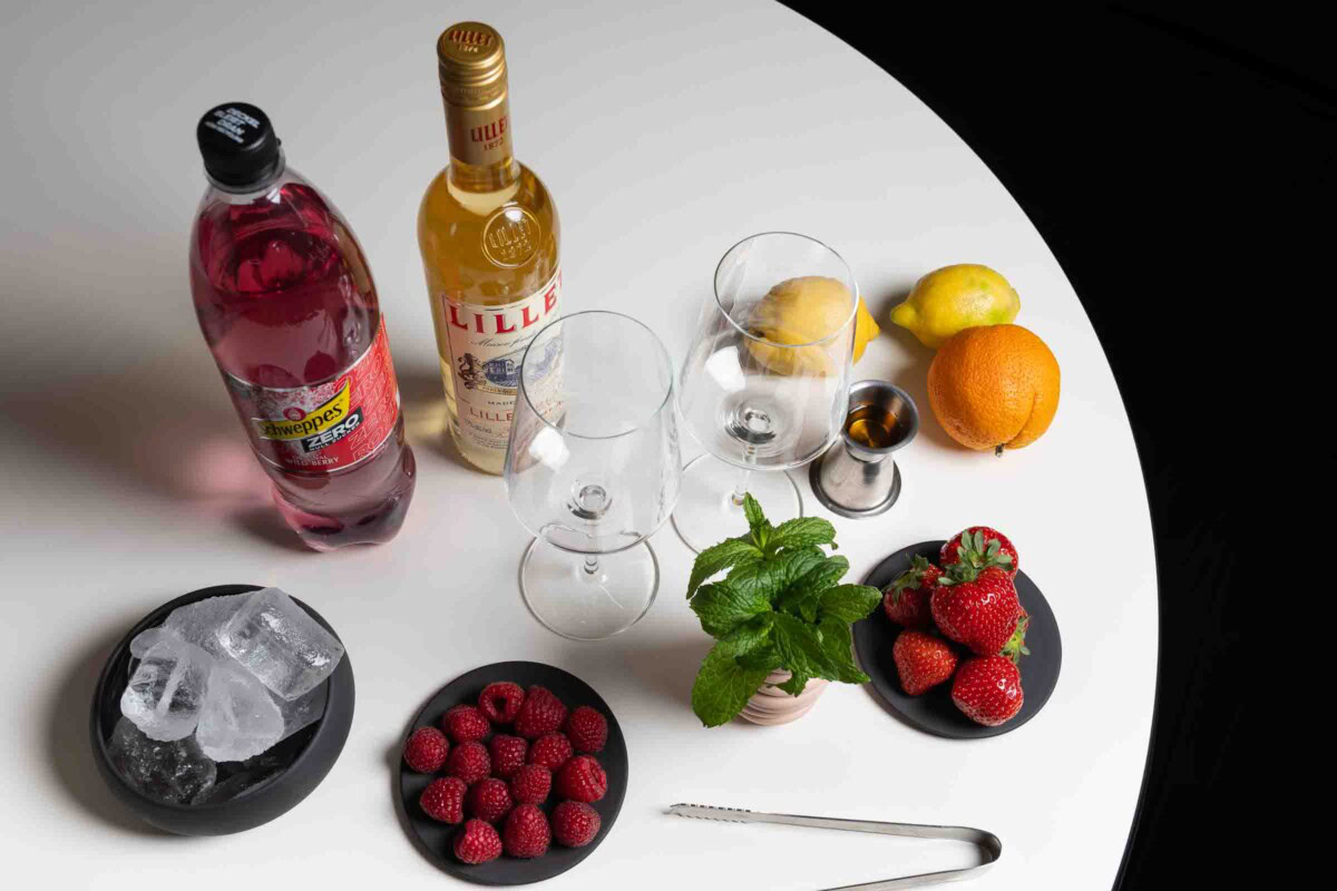 Zutaten für Lillet Wild Berry Cocktail auf einem Tisch arrangiert