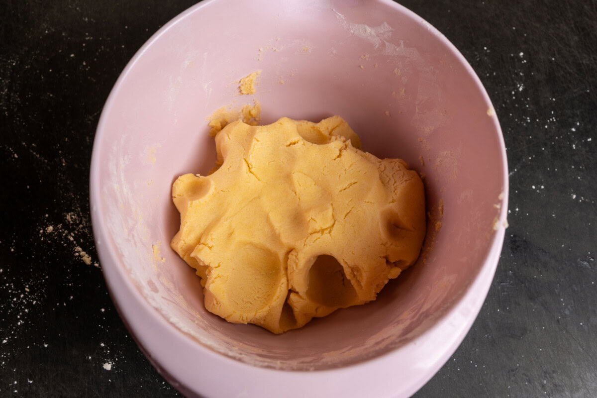Fertig gekneteter Mürbeteig in einer rosa Rührschüssel.