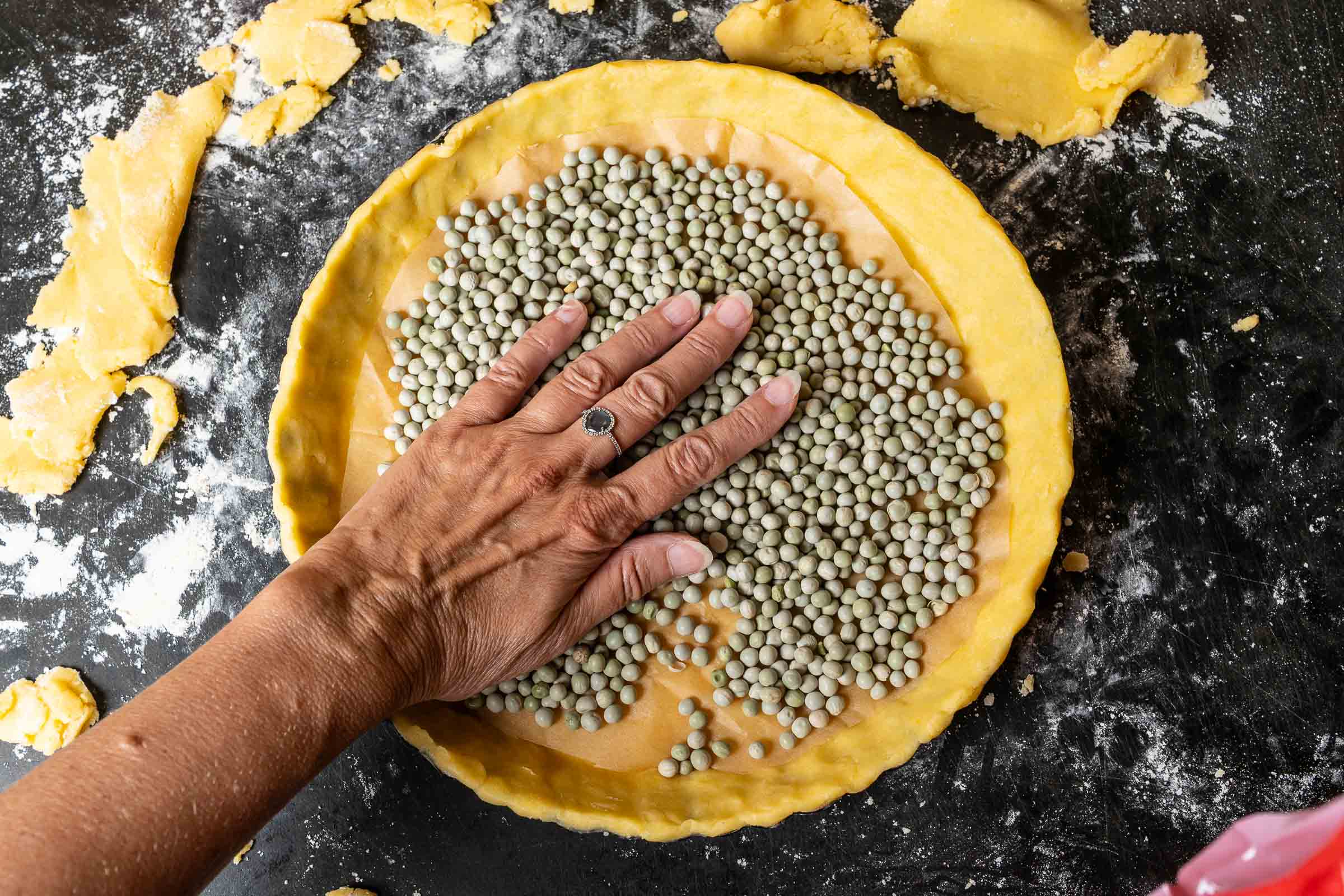 Mürbteig blind backen: Tarteboden mit Backpapier und getrockneten Erbsen zum Blindbacken.