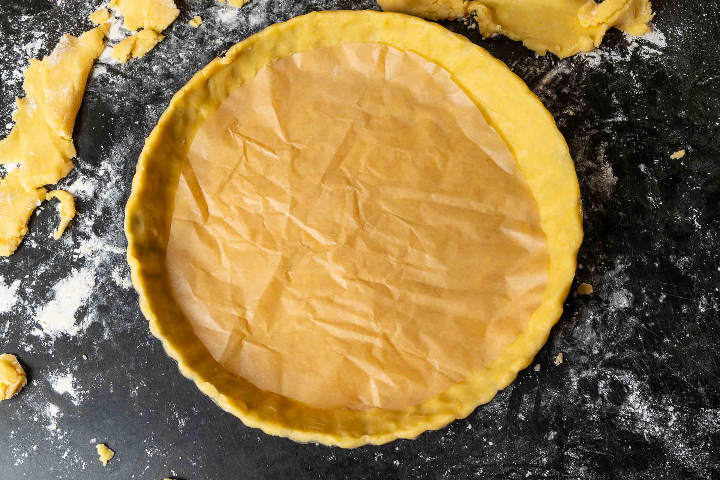 Tarteboden mit Backpapier ausgelegt vor dem Blindbacken.