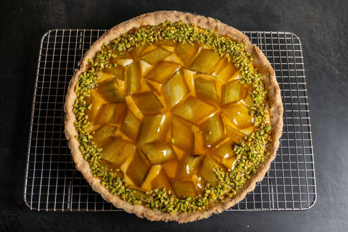 Rhabarber-Tarte mit Aprikosenglasur und Pistazienrand auf Gitter abgekühlt