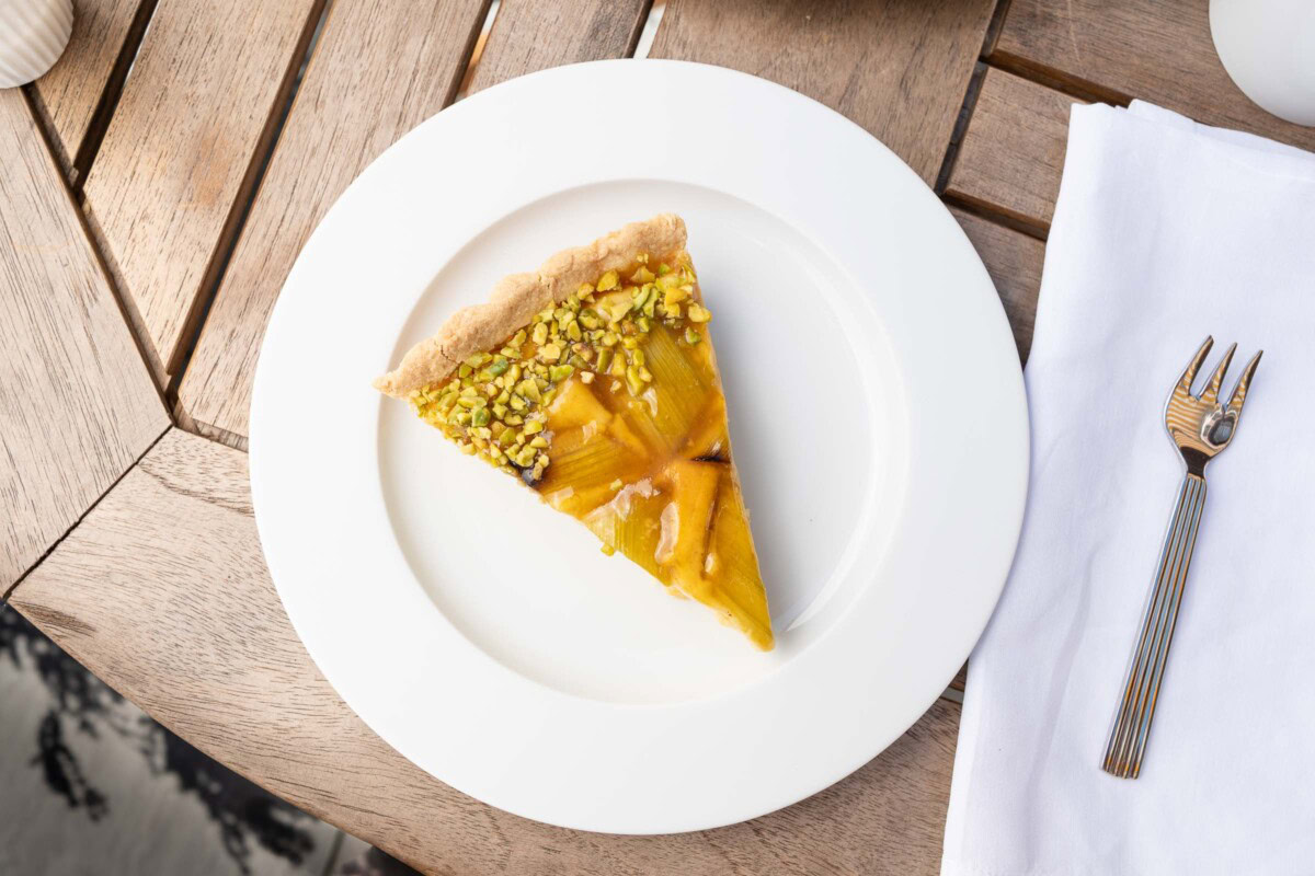 Rhabarber-Tarte-Stück mit Pistazien von oben auf weißem Teller